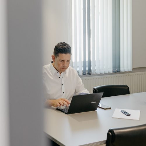 datev-digitale-kanzlei-schicker Stefan Schuler arbeitet in einem Besprechungsraum an seinem Laptop.